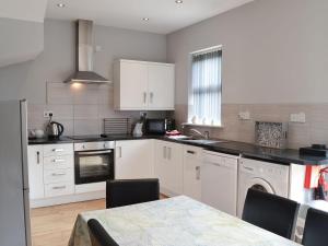 a kitchen with white cabinets and a table with chairs at Lynbank in Seahouses