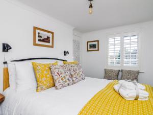 a bedroom with a white bed with yellow sheets and pillows at Church View Cottage in Goudhurst