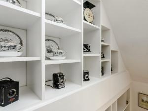 a room with white shelves with dishes and a clock at Church View Cottage in Goudhurst