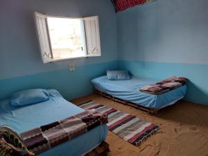 two beds in a blue room with a window at ارجوندي جيست هاوس in Aswan