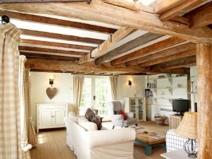 a living room with white furniture and wooden ceilings at Prospect Cottage in Wittersham