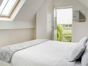 a white bedroom with a bed and a window at Swallows Nest in Bibury