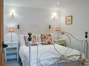 a bedroom with a white bed with two tables and two lamps at Manor Cottage in Nymet Tracey