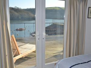 a bedroom with a door to a balcony with a view of the water at Lower Deck in Fowey
