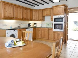 cocina con armarios de madera y mesa de madera en 2 Sawmill Cottages, en Puncknowle