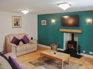 ein Wohnzimmer mit einem Sofa und einem Kamin in der Unterkunft Tayberry Cottage in Aberfeldy