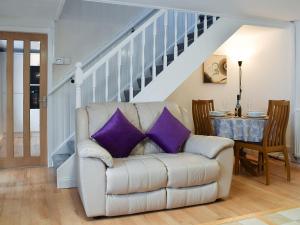 ein weißes Sofa mit lila Kissen im Wohnzimmer in der Unterkunft Tayberry Cottage in Aberfeldy