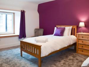 ein Schlafzimmer mit einem Bett und einer lila Wand in der Unterkunft Tayberry Cottage in Aberfeldy