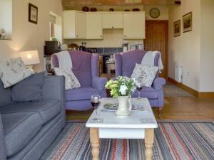 ein Wohnzimmer mit zwei lila Sofas und einem Tisch in der Unterkunft The Cart Lodge in Hooe