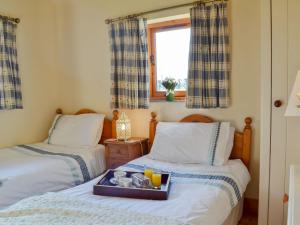 2 Betten in einem Zimmer mit einem Tablett mit Essen drauf in der Unterkunft The Cart Lodge in Hooe