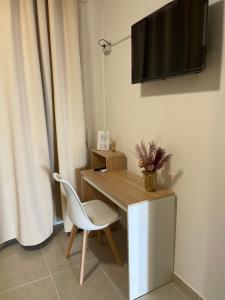 a desk with a chair and a television on a wall at Mura Guest Room in Terralba