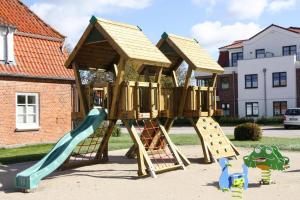 a wooden play structure with a slide and a slideintend at Appartements im Avalon Hotel Bellevue, Fehmarn in Fehmarn