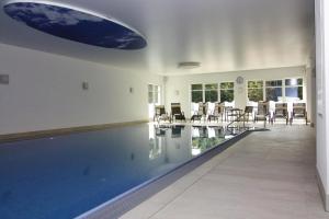 a swimming pool in a house with chairs and tables at Appartements im Avalon Hotel Bellevue, Fehmarn in Fehmarn