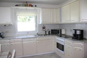 a kitchen with white cabinets and a sink and a window at Ferienhaus Perle am Fuße der Augustusburg in Augustusburg