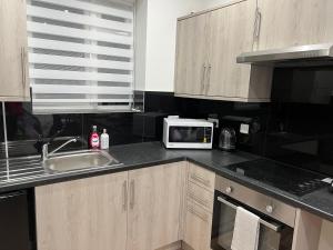 una cucina con forno a microonde e lavandino di Park View Serviced Apartment - Next to Northolt Tube Station - Near Central London & Wembley a Northolt