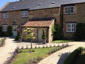 a brick house with a garden in front of it at The Old Coach House in Ripon