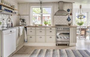 uma cozinha com armários brancos e um forno com placa de fogão em 4 Bedroom Cozy Home In Ells em Ellös