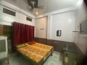 Habitación pequeña con cama y cortina roja en Yatri niwas home stay en Varanasi
