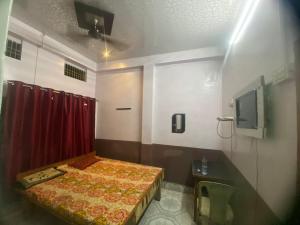 Habitación pequeña con cama y cortina roja en Yatri niwas home stay en Varanasi