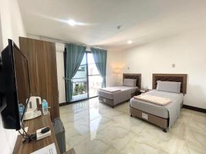 パングラオにあるMGH Alona Resortのベッド2台とテレビが備わるホテルルームです。