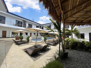 a resort with a pool with lounge chairs and umbrellas at MGH Alona Resort in Panglao Island