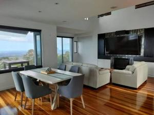 a living room with a table and chairs and a tv at Coastline: Alpine Villa in Mount Tamborine