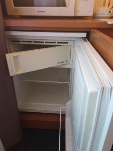 una nevera con la puerta abierta y un microondas en ALKA apartaments, en Palanga