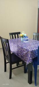 uma mesa roxa com duas cadeiras e uma toalha de mesa roxa em HOMESTAY KAKMAH em Jasin