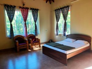 um quarto com uma cama, 2 cadeiras e janelas em Memories of Malnad em Chikmagalur