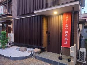 Yadoya Matsumoto Honjo - Vacation STAY 13372v في ماتسوموتو: مبنى عليه باب احمر وعلامة عليه