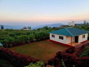 a small house with a green roof and a yard at RUDRASHREE VILLA - Besides Valley View in Mahabaleshwar