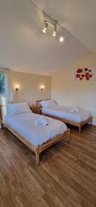2 łóżka w pokoju z drewnianą podłogą w obiekcie Willow by Paymán Club w mieście Royston