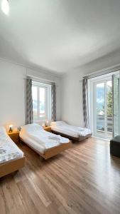 ダボスにあるVilla Zentrum Haus Davosのウッドフロアの客室で、ベッド3台、窓が備わります。