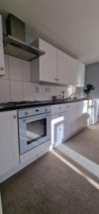 a kitchen with white cabinets and a stove at Maple by Paymán Club in Royston