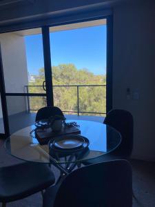 una mesa de cristal y sillas en una habitación con ventana en Bright 1 Bedroom Joondalup Stay, en Perth