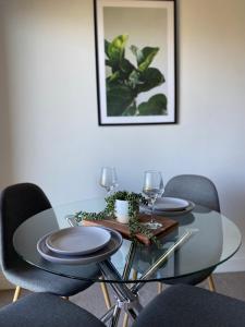a dining room table with chairs and a glass table with glasses at Bright 1 Bedroom Joondalup Stay in Perth