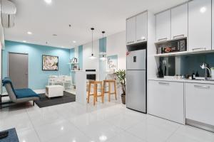 uma cozinha com armários brancos e uma parede azul em Summer Suites KLCC Apartments by soulasia em Kuala Lumpur