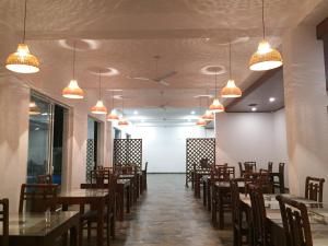 Un comedor con mesas, sillas y luces. en ARA Beach Resort Mirissa, en Mirissa