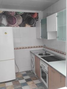cocina blanca con fregadero y lavavajillas en En el corazón de la ciudad en Badajoz