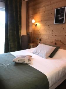 a bedroom with a large bed with a wooden wall at Le Ptit Hotel du Lac in Gérardmer