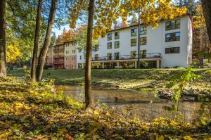 duży biały budynek z drzewami przed nim w obiekcie Hotel Mir-Jan SPA w mieście Lądek-Zdrój