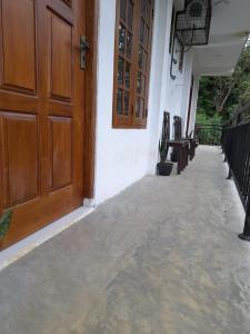 a walkway outside of a house with a wooden door at Water Side Guest in Adams Peak