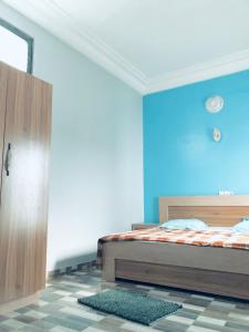 1 dormitorio con cama y pared azul en Superbe maison dans un quartier calme - Bénin, en Ekpé