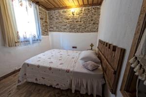 ein Schlafzimmer mit einem Bett in einem Zimmer mit einer Steinmauer in der Unterkunft Birgi Hotel Saliha Hanim Tas Konak in Birgi