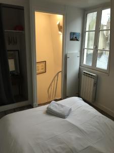 1 dormitorio con 1 cama blanca y ventana en La plus petite maison de pêcheur de Trouville-sur-mer, en Trouville-sur-Mer
