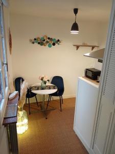 una pequeña cocina con mesa, sillas y barra. en La plus petite maison de pêcheur de Trouville-sur-mer, en Trouville-sur-Mer
