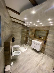 a bathroom with two sinks and a toilet and a shower at Motel pizzeria Antic's in Laktaši