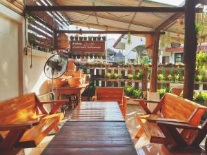 un restaurant avec des bancs en bois, une table et des chaises dans l'établissement เฮือนน่านนิทรา, à Nan