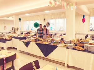 two people standing at a buffet table with food at Hotel Riposo in Gatteo a Mare