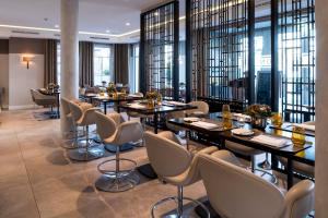 a restaurant with tables and chairs and windows at Strandhotel Fontana in Timmendorfer Strand